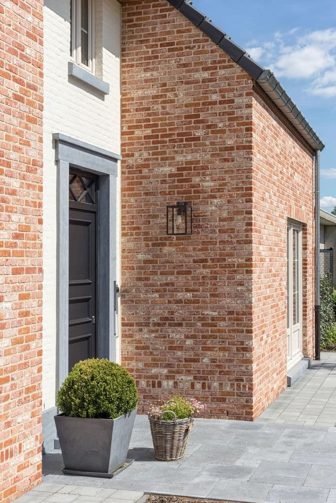 Un ingresso di casa tra mattoni, una porta e piante verdi